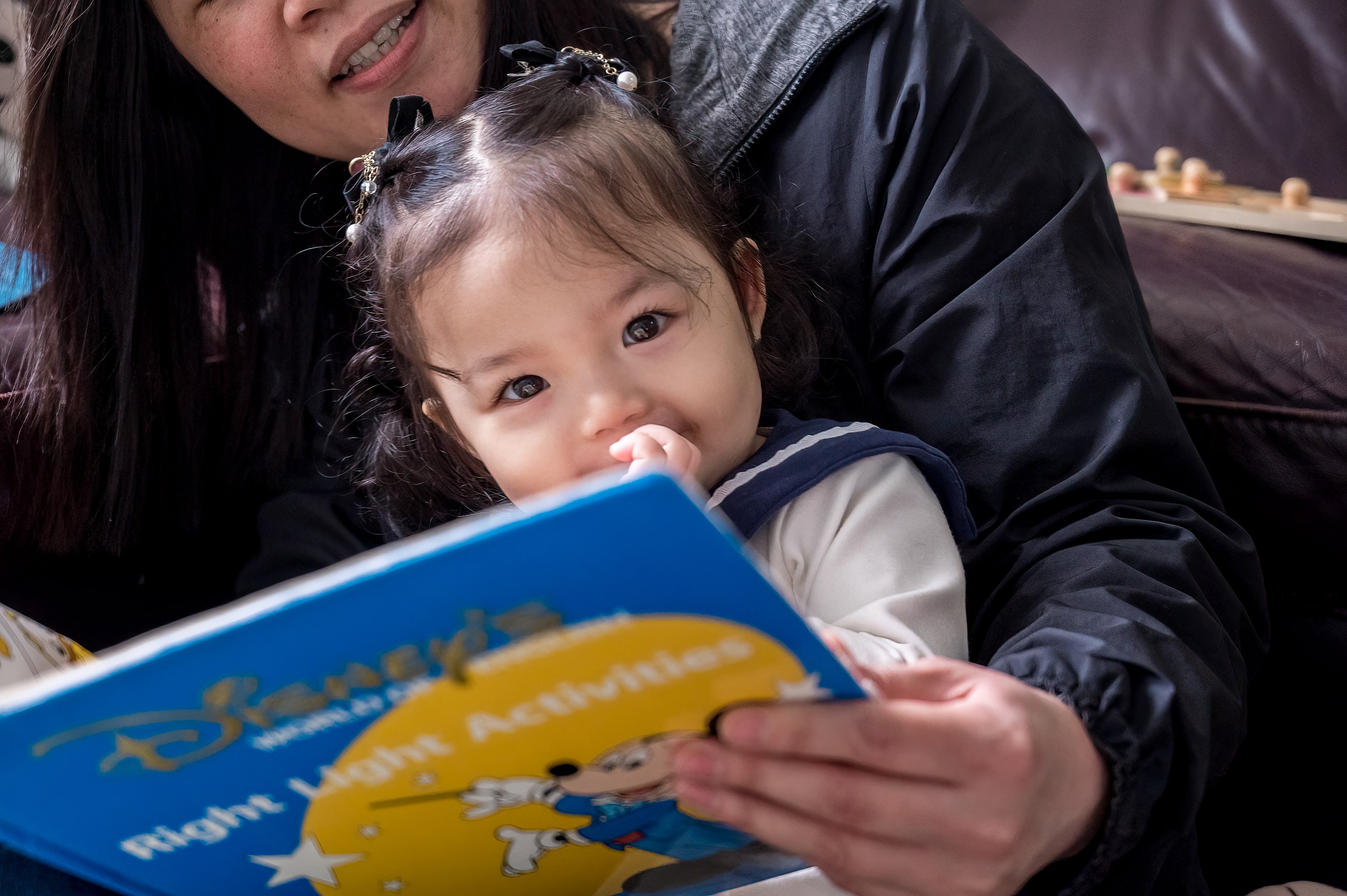 一個孩子在媽媽的教導及陪伴下看英文書。